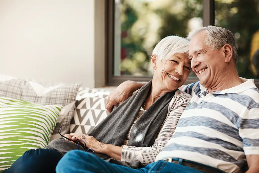 Senior woman cuddling with her husband at their 55+ apartment home in a senior living community. 
